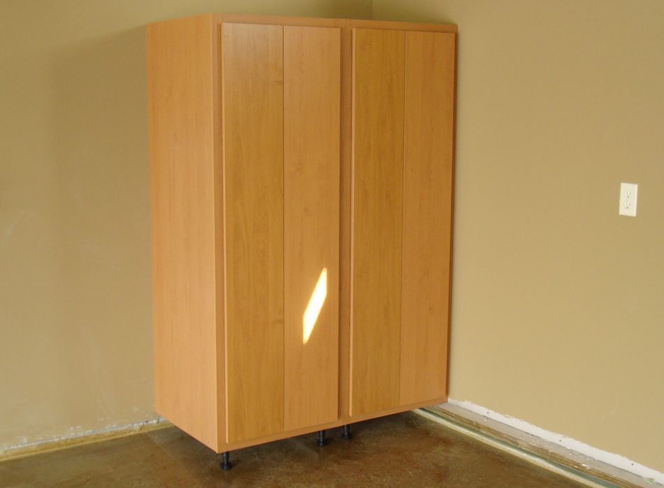 Tan wooden storage cabinet in a corner against beige walls.