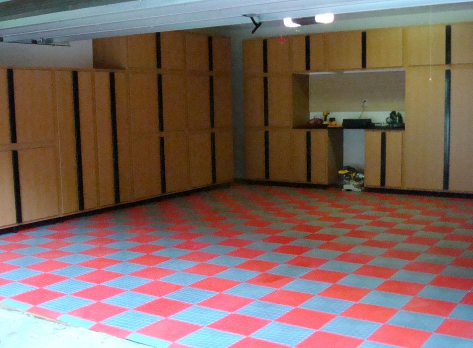 Garage interior with red and gray checkered floor, tan cabinets, and a workstation area.