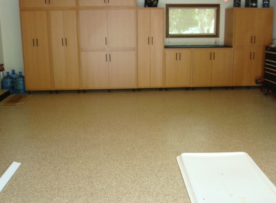 Garage with tan floor, light brown cabinets, and a window.