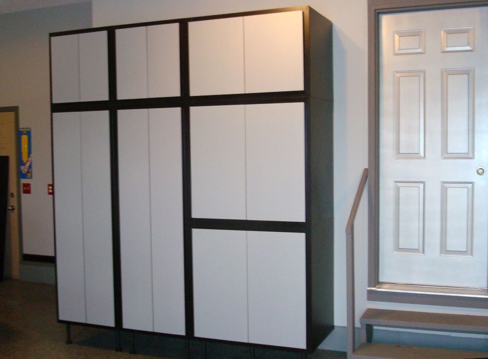 Large white and black storage cabinet with multiple doors, beside a door with gray trim.