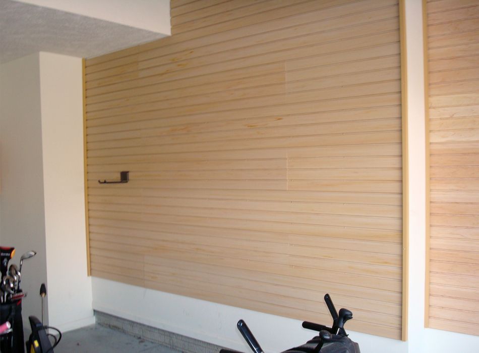 Wooden plank wall in a garage, with a white pillar and a gray concrete floor.