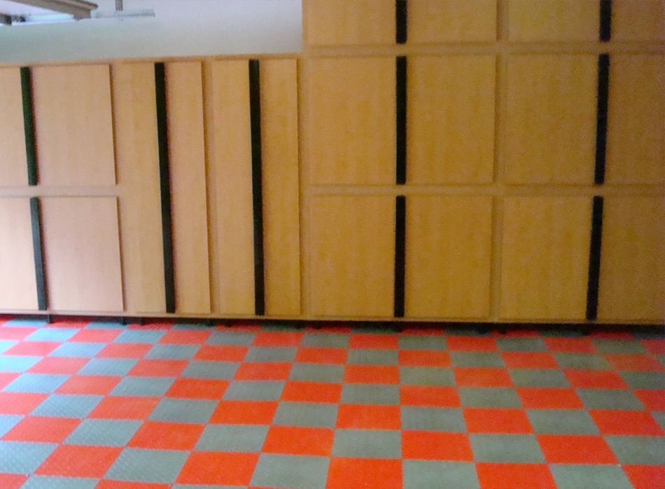 Garage interior with checkerboard floor and wooden storage cabinets.