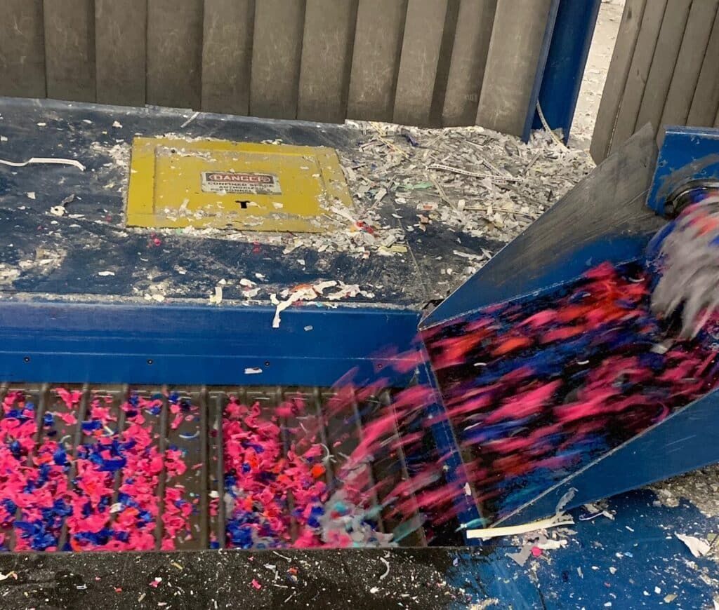 Recycling conveyor sorting colorful shredded plastic.
