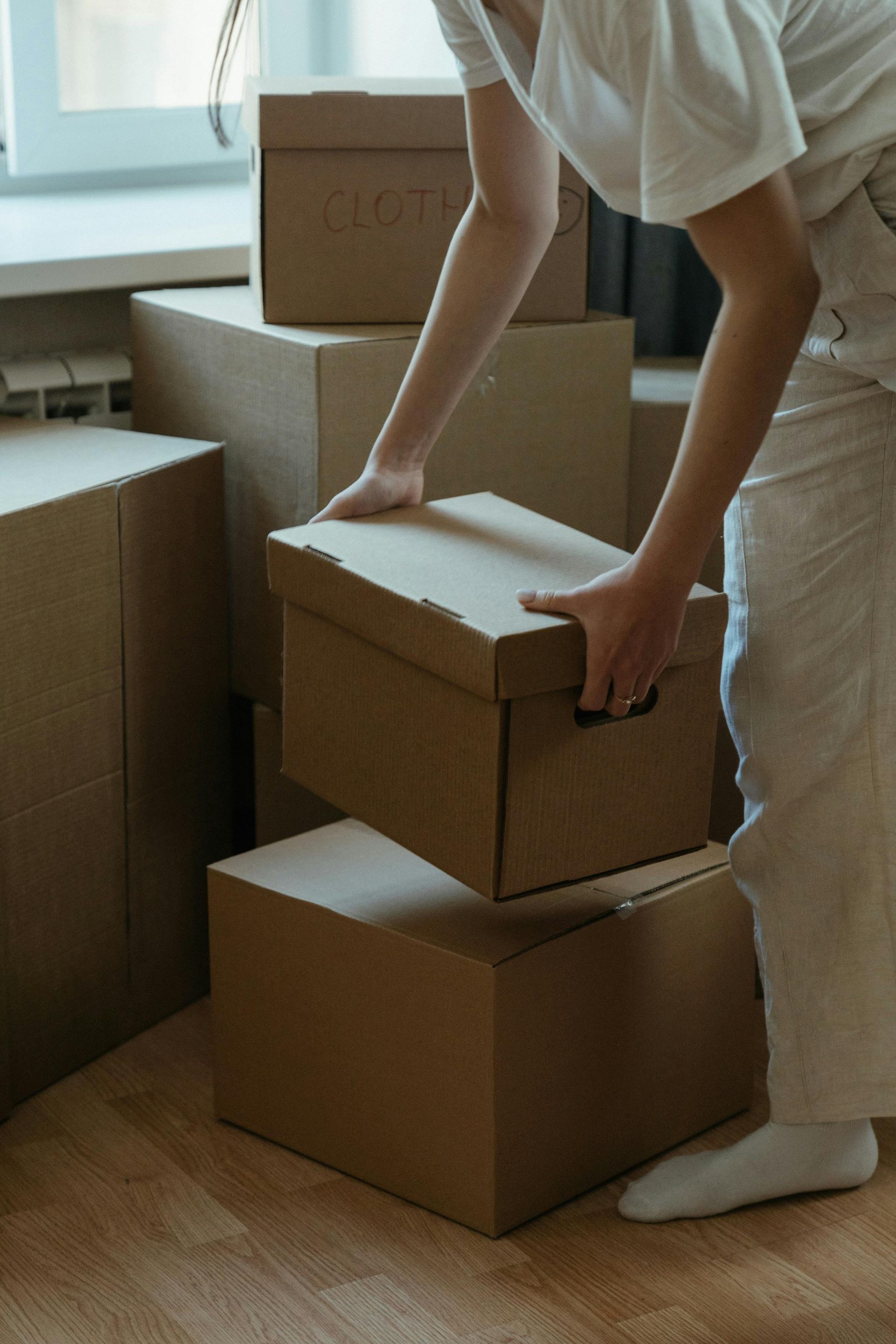 Person stacking cardboard boxes indoors.