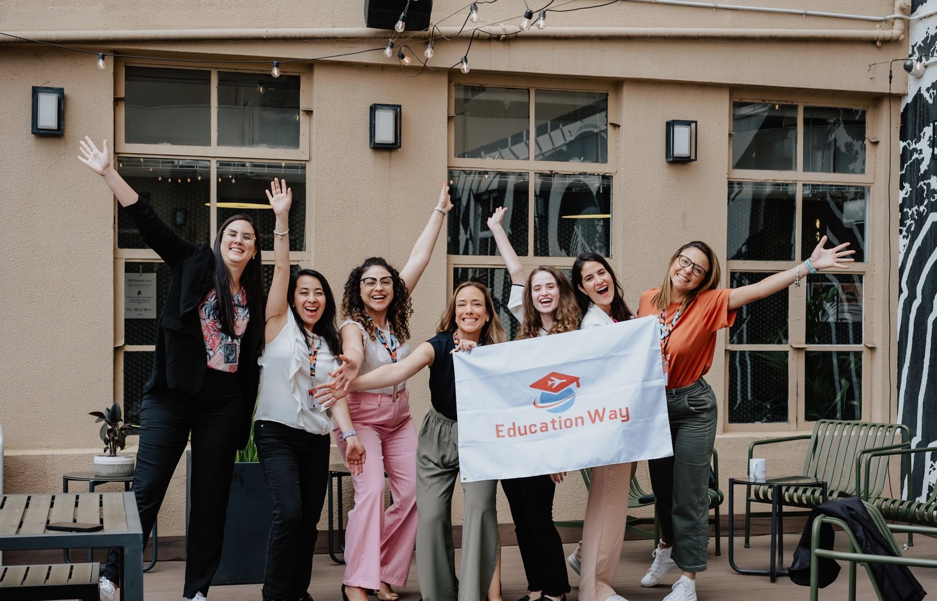 Grupo de mulheres comemorando ao ar livre, segurando uma bandeira com a inscrição