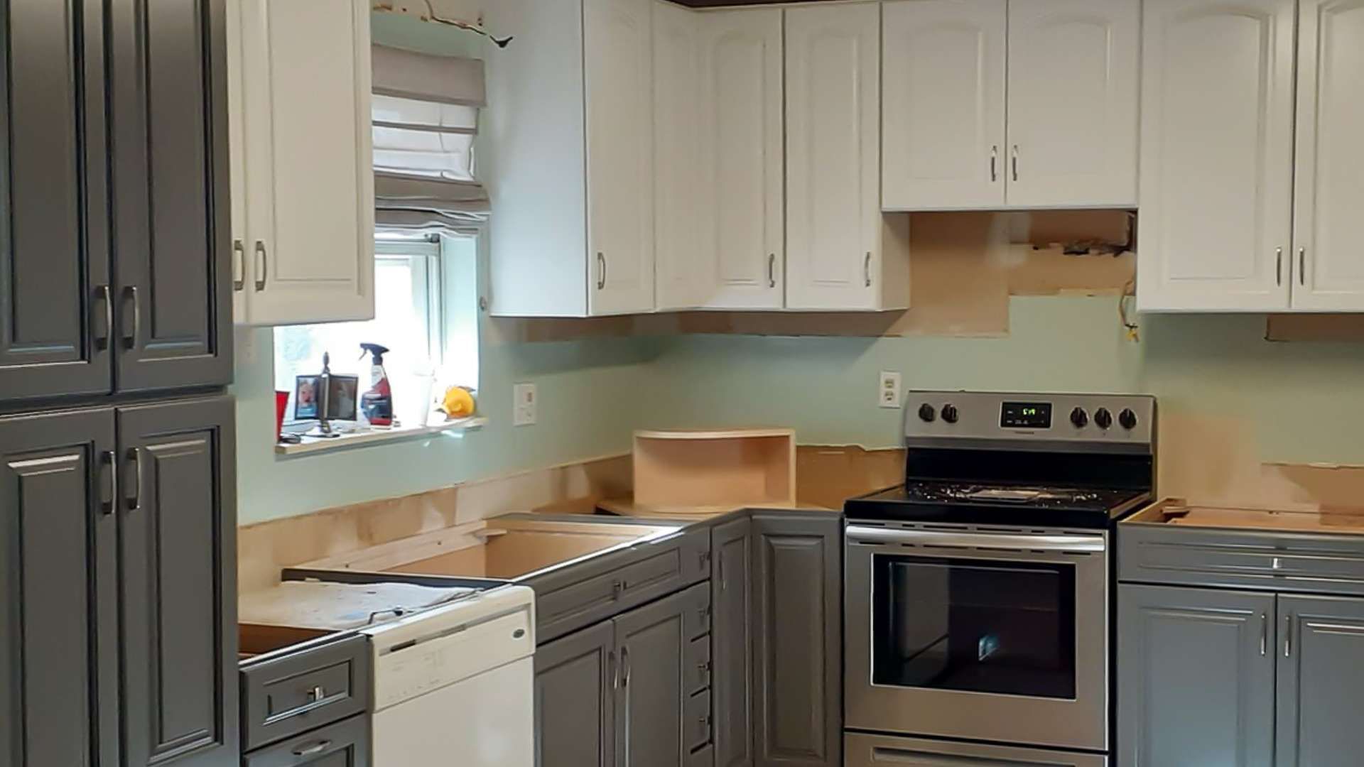 A kitchen with gray cabinets, white cabinets, a stove and a dishwasher.