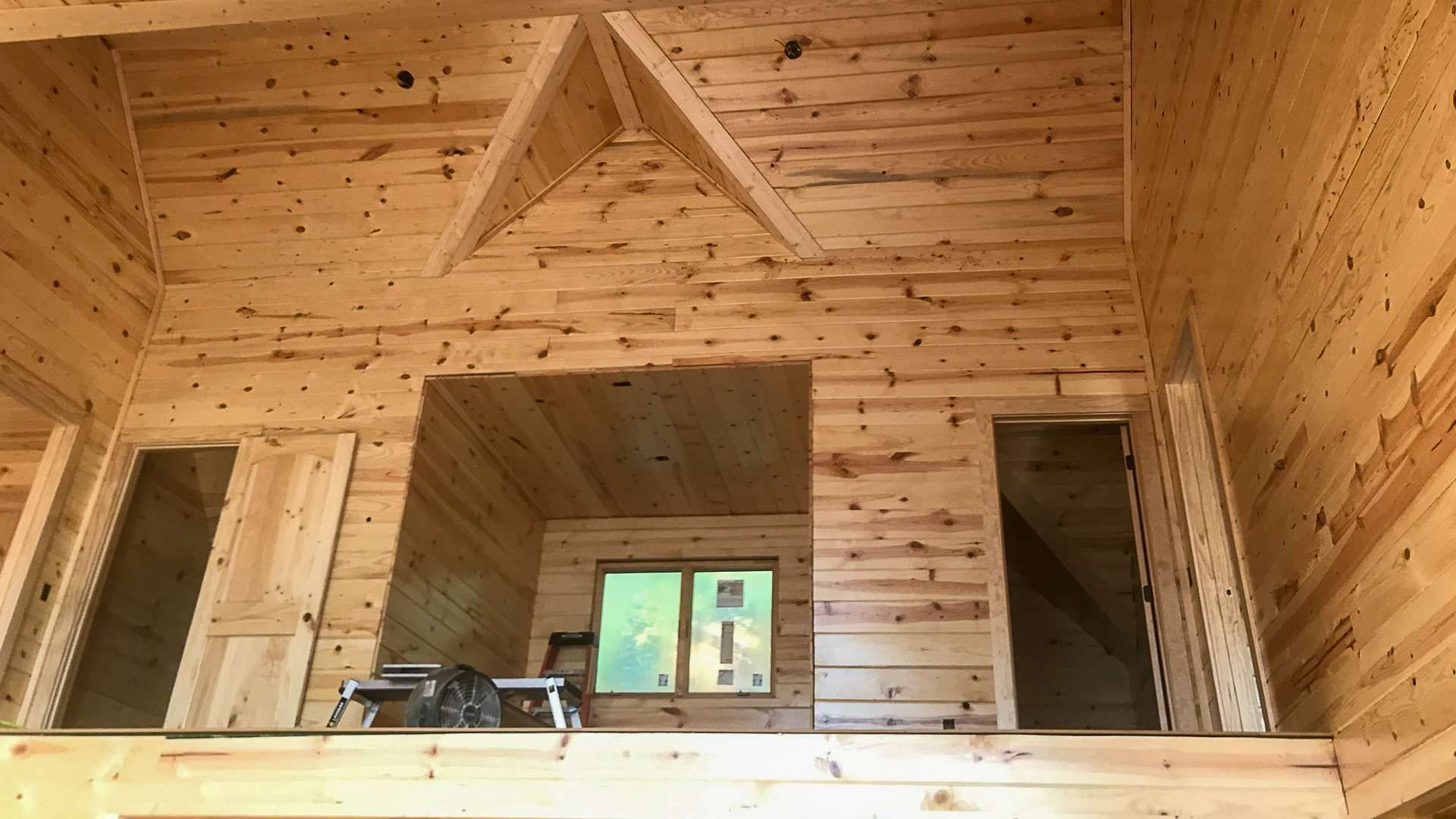 The inside of a log cabin with a wooden ceiling and walls.