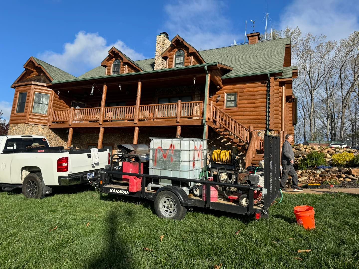 Two trucks are parked in front of a large log cabin.