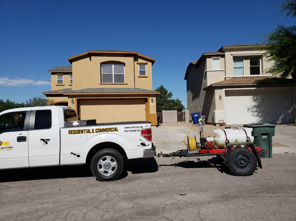 White pickup towing equipment trailer in front of two houses on a sunny street