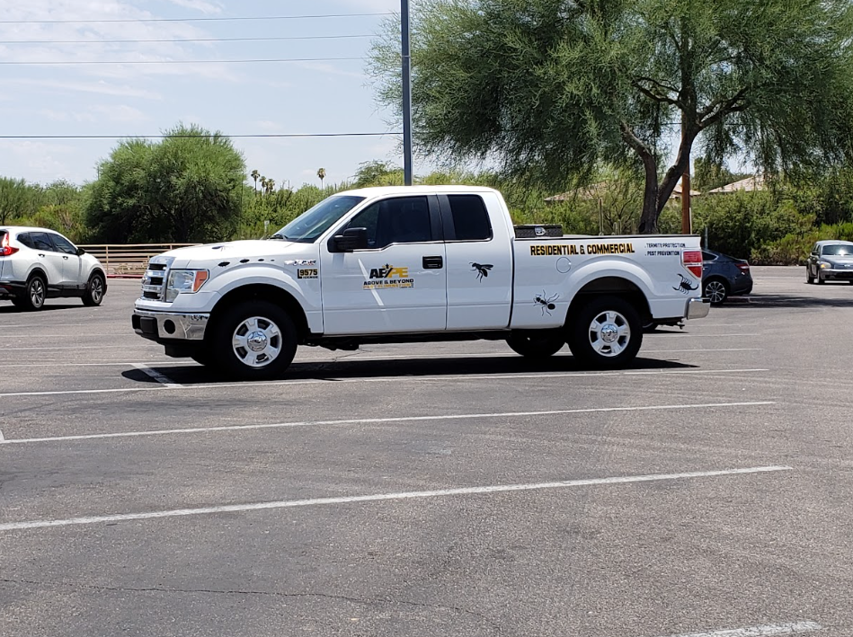 White tow truck parked in a sunny lot with trees and other cars in the background