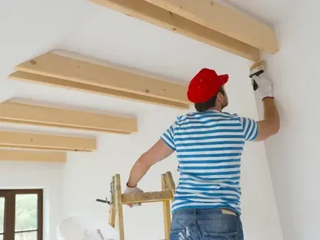 A man is standing on a ladder painting a wall.