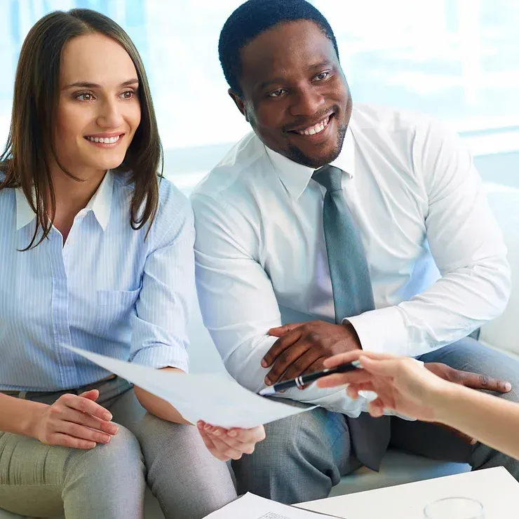 A man and a woman are sitting on a couch looking at a piece of paper