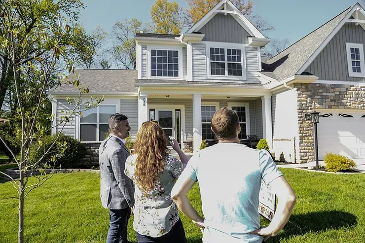 A group of people are standing in front of a house.