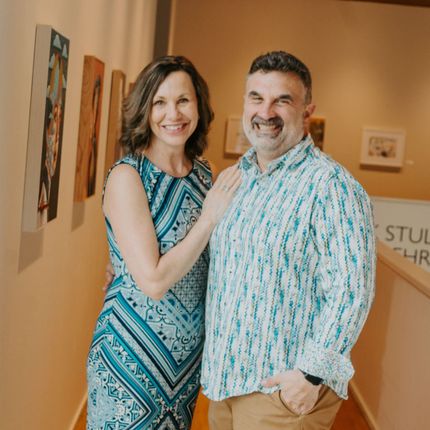 A man and a woman are posing for a picture in a hallway