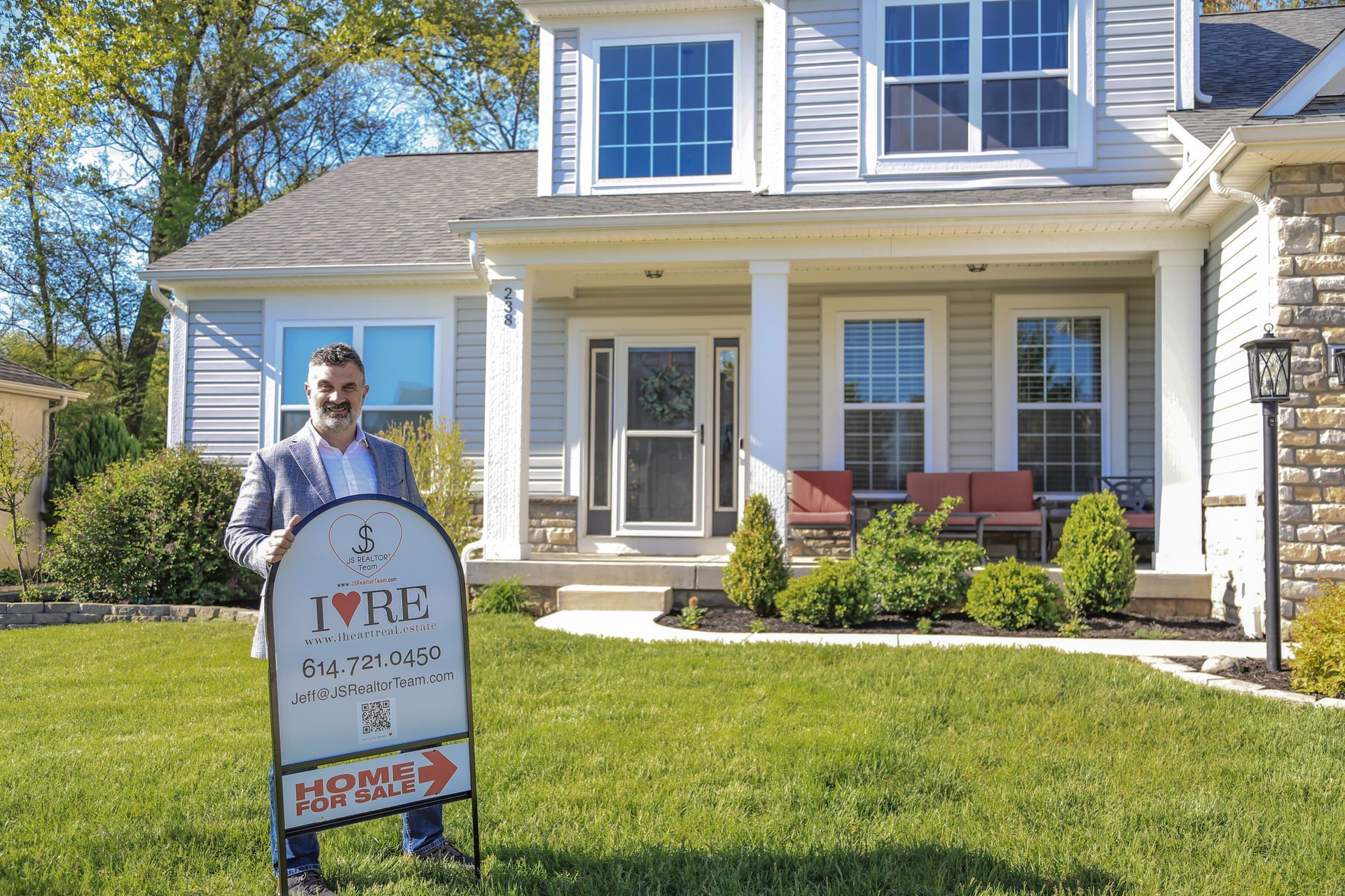 A man is holding a sign in front of a house.