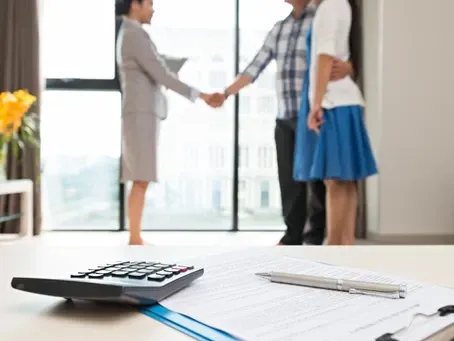 A woman is shaking hands with a man and woman in a living room.