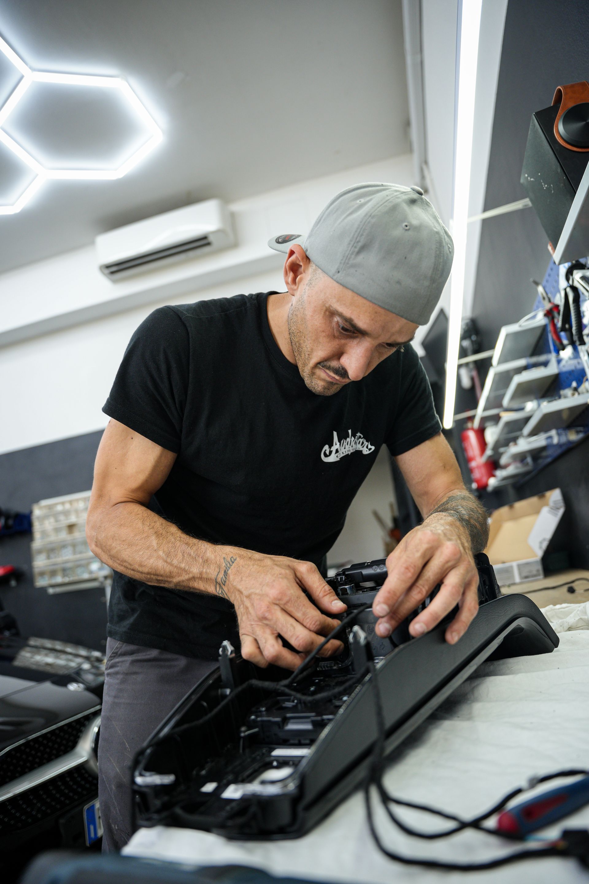 Un automobilista regola i comandi del cruscotto all'interno della propria auto, mentre un altro veicolo è visibile davanti a lui attraverso il parabrezza.