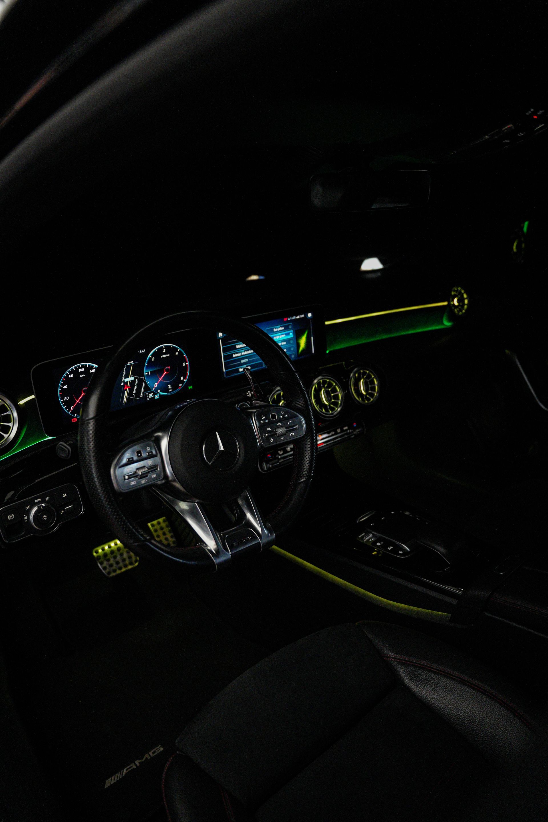 Interni di un'auto di notte con illuminazione a LED viola su cruscotto, console centrale e pavimento.
