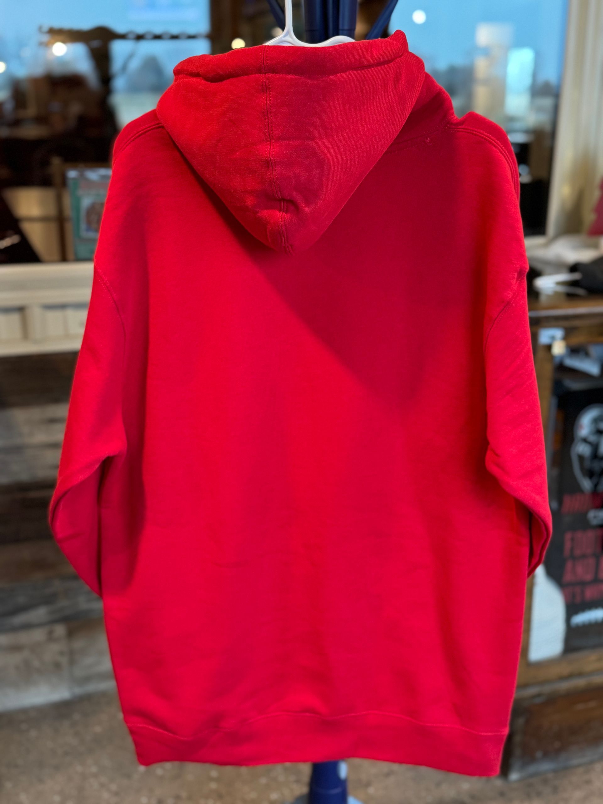 Red hoodie with a white logo, hanging on a white hanger. The logo includes the word 