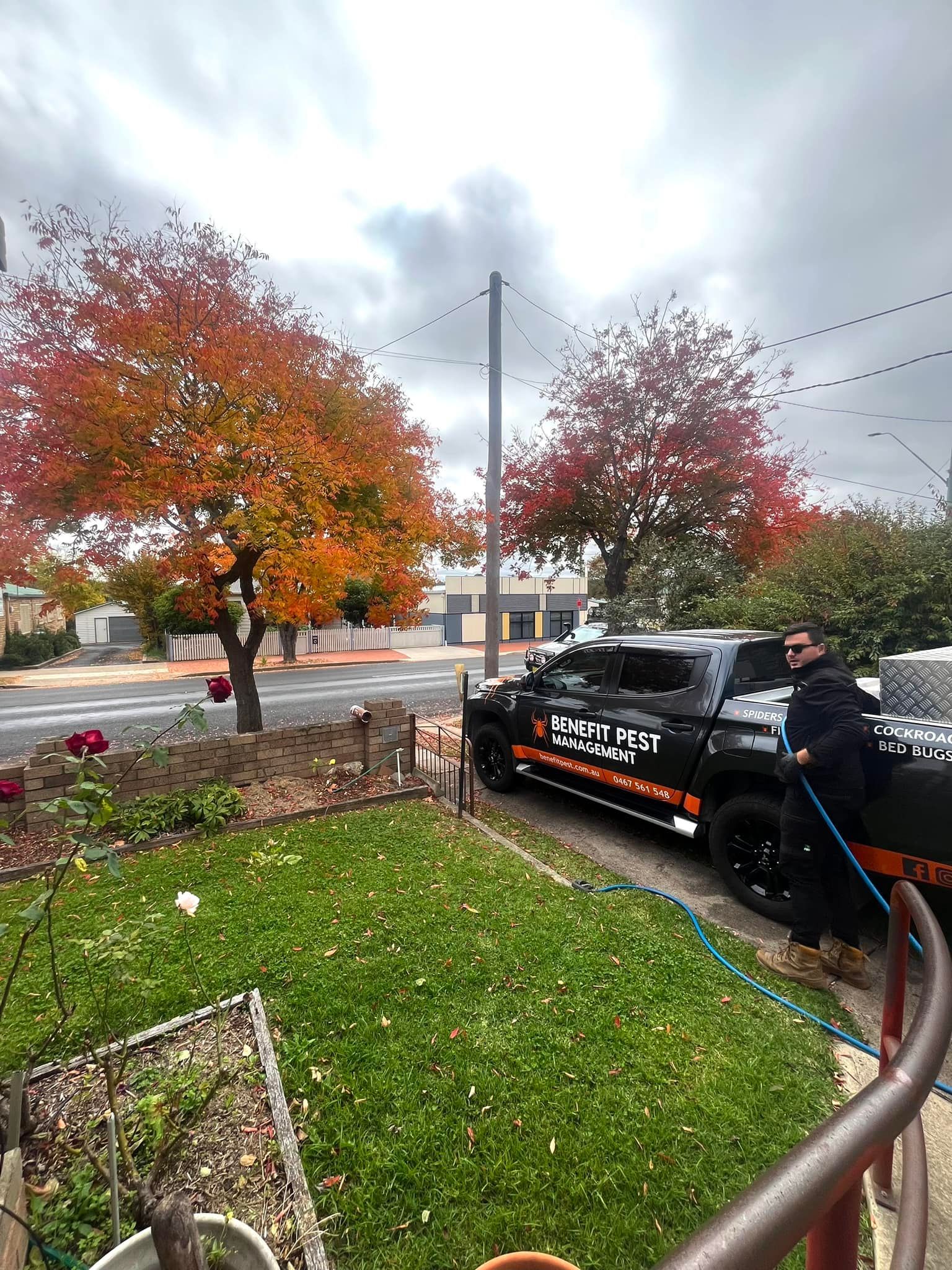 A Man Is Washing a Truck with A Hose in Front of A House — Benefit Pest Management Pty Ltd in Balcolyn, NSW