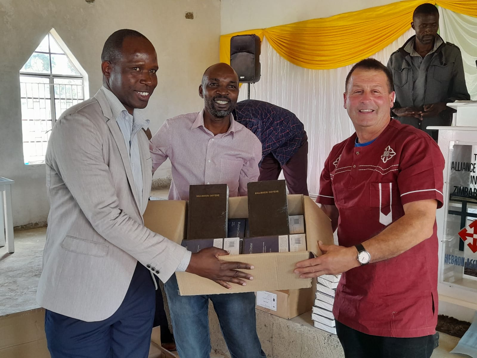 A man in a maroon shirt is holding a box of books