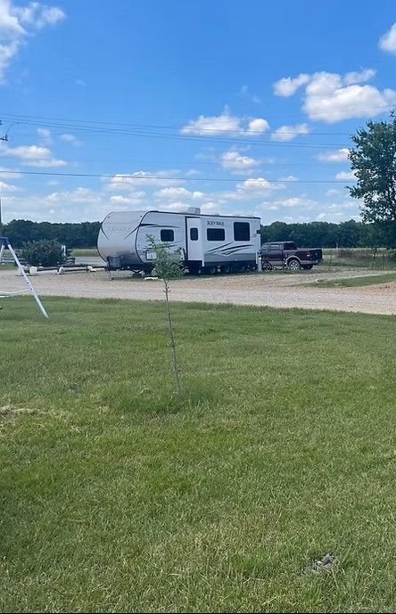 A white travel trailer parked on a gravel lot under a bright blue sky. A white travel trailer parked on a gravel lot under a bright blue sky.