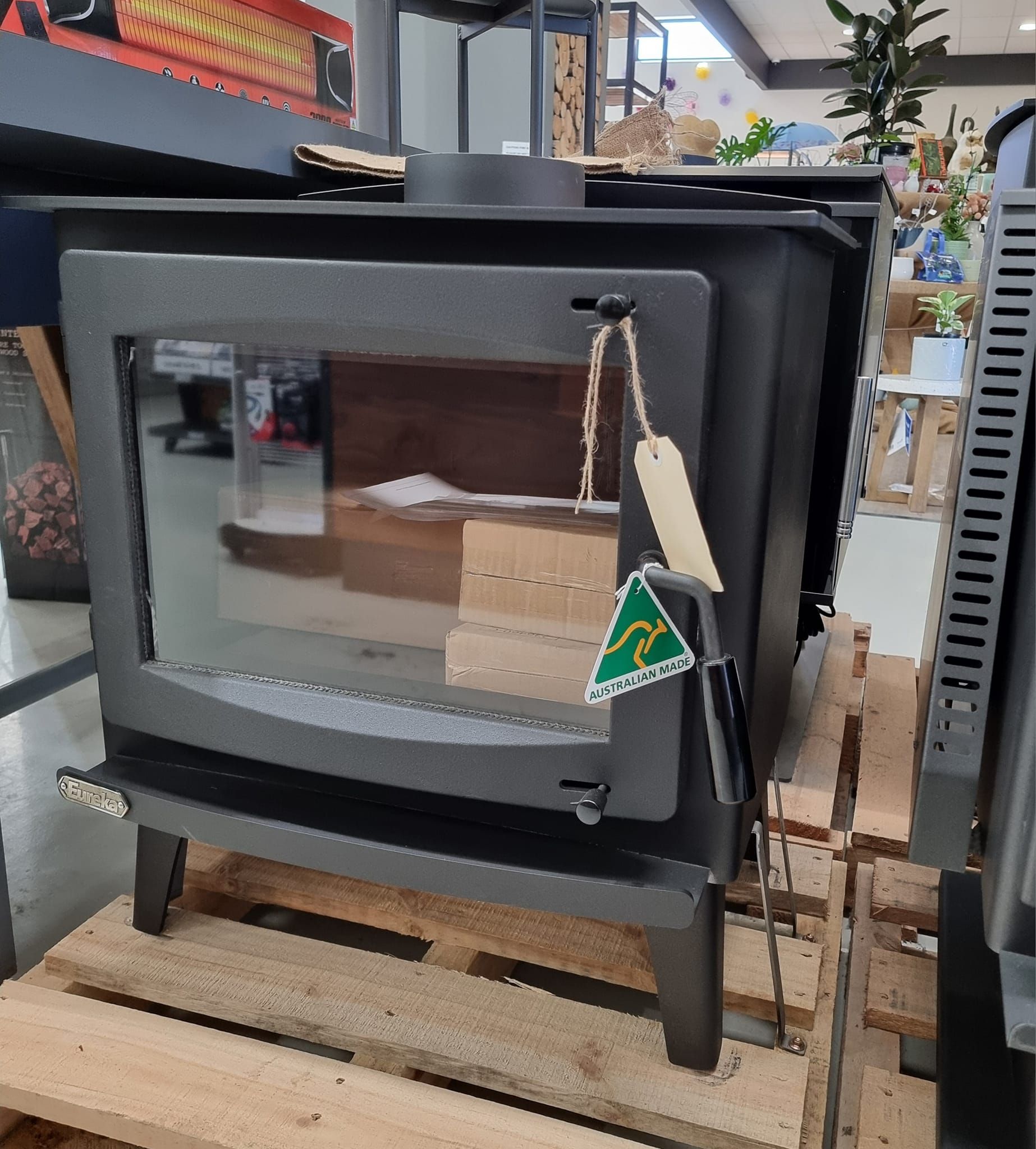 A wood stove is sitting on a wooden pallet in a store.
