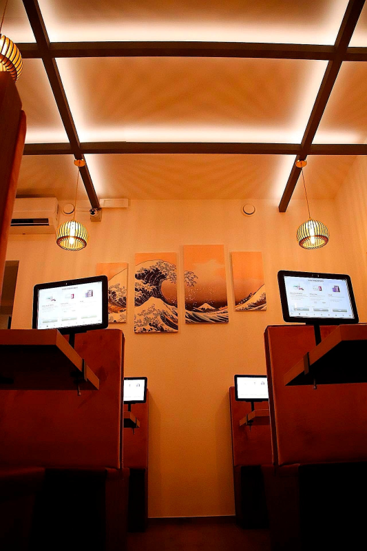 Cabina con illuminazione calda, due schermi per computer, pannelli in legno e un'opera d'arte astratta sulla parete di fondo.