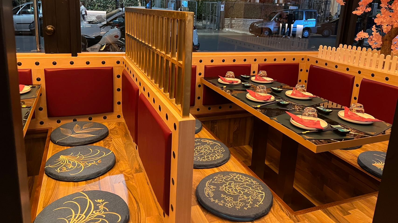 All'interno di un ristorante, divanetti arancioni con cuscini rotondi e un tavolo di legno apparecchiato con piatti.