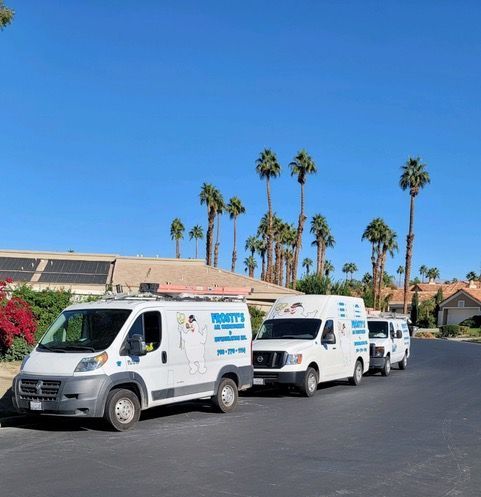 A row of white vans are parked on the side of the road.