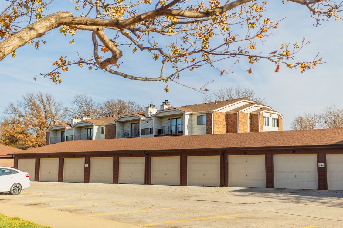 A white car is parked in front of a row of garages.
