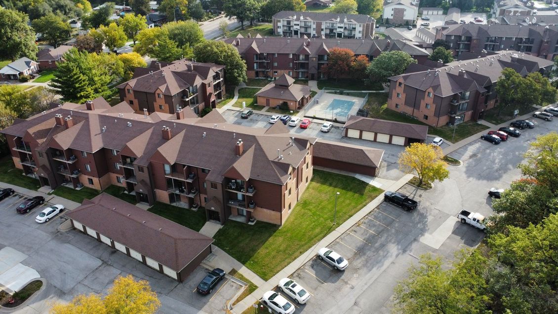 An aerial view of a apartment complex with cars parked in front of it.
