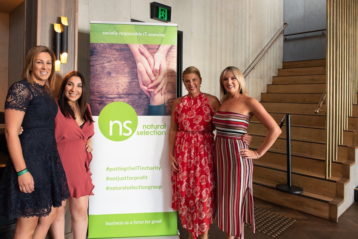 Four people stand smiling next to a branded 