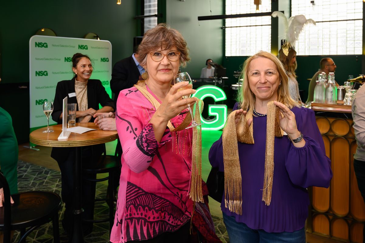 Two people toast at a social event with a green 