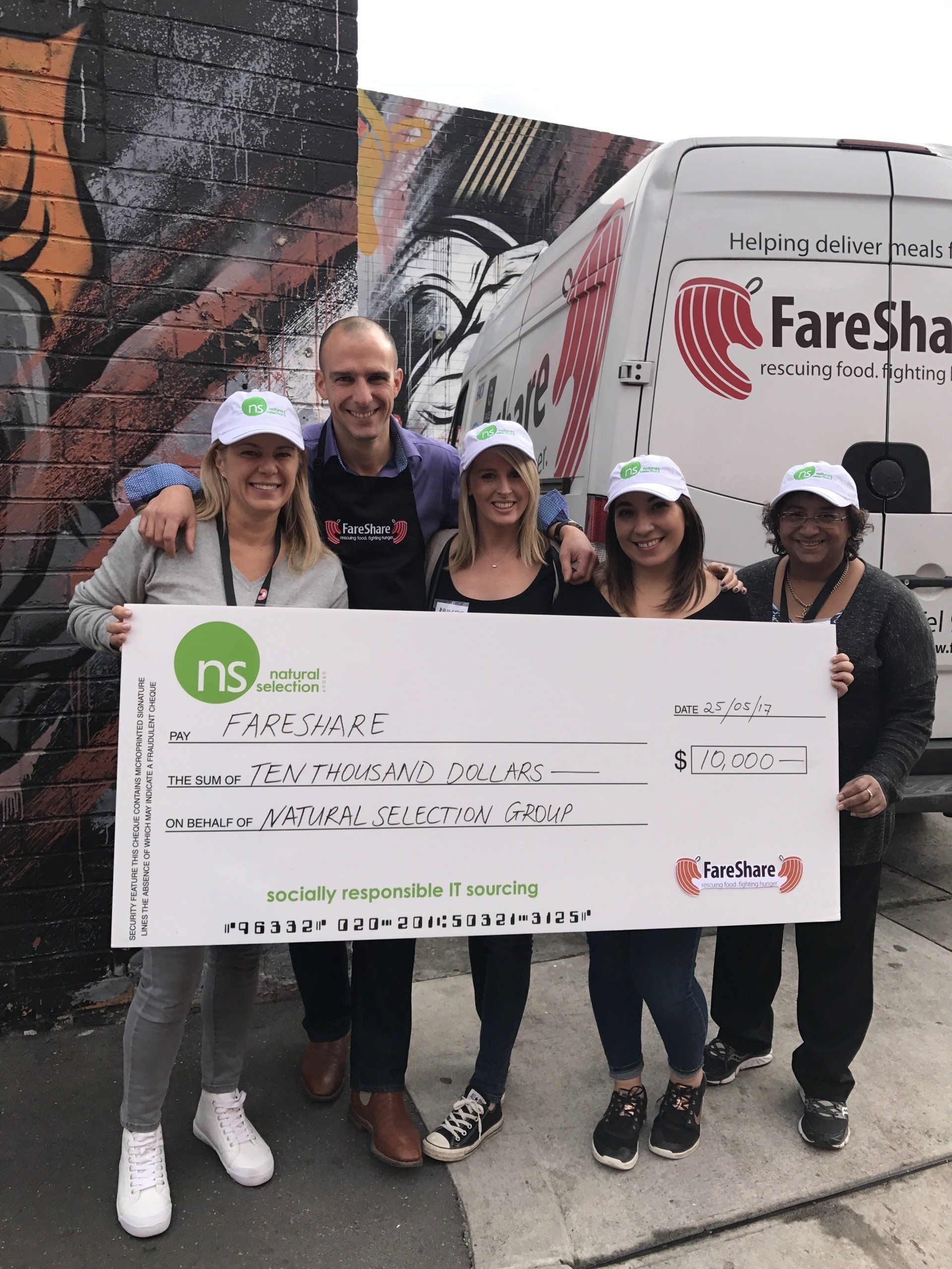 Five people hold a large novelty donation check from 