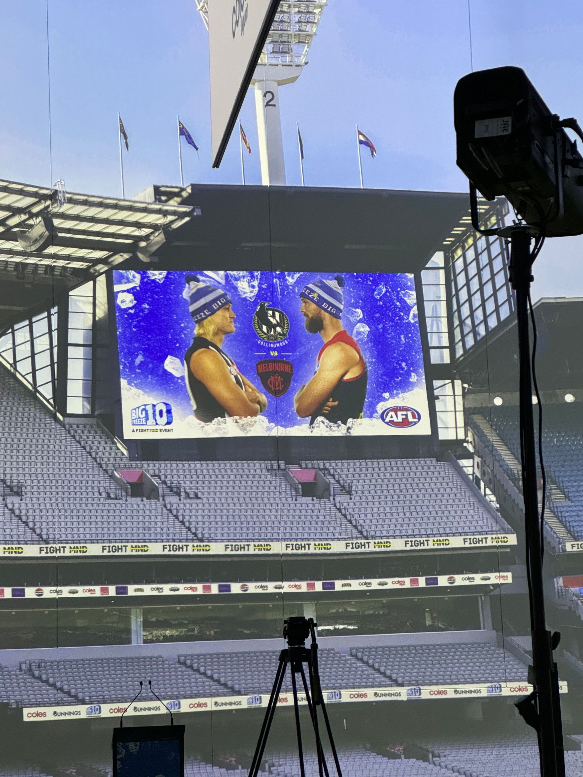 A large stadium screen displays two players wearing winter beanies, set against a blue, snowy-themed graphic.
