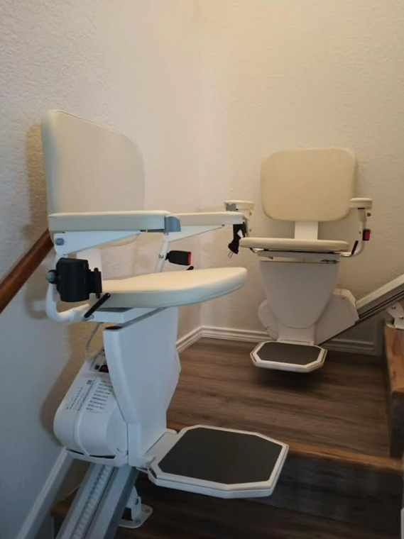 Two beige stairlifts installed on a staircase with a wood floor and white walls.