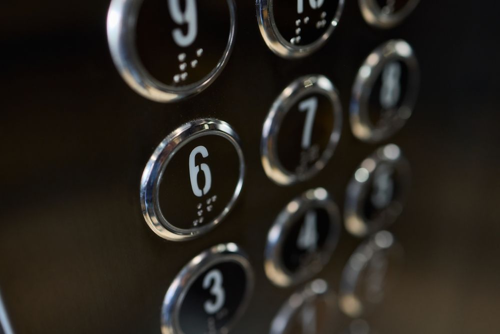 Close-up of a chrome elevator button panel with illuminated floor numbers.