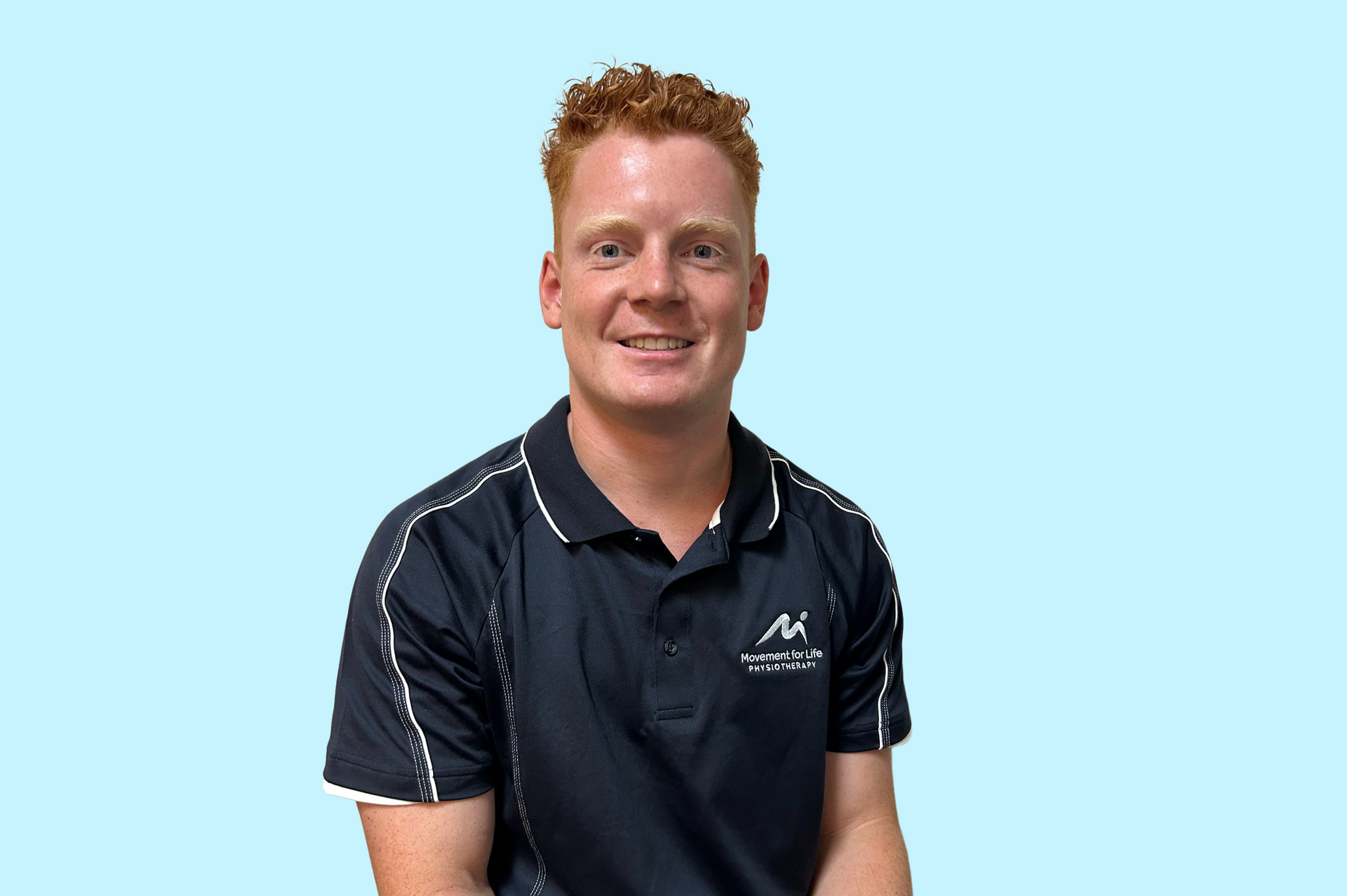 Smiling person in a navy polo shirt against a teal background