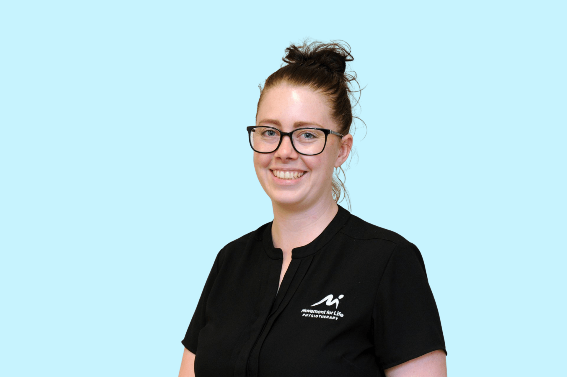 Smiling person wearing glasses and a black shirt against a teal background