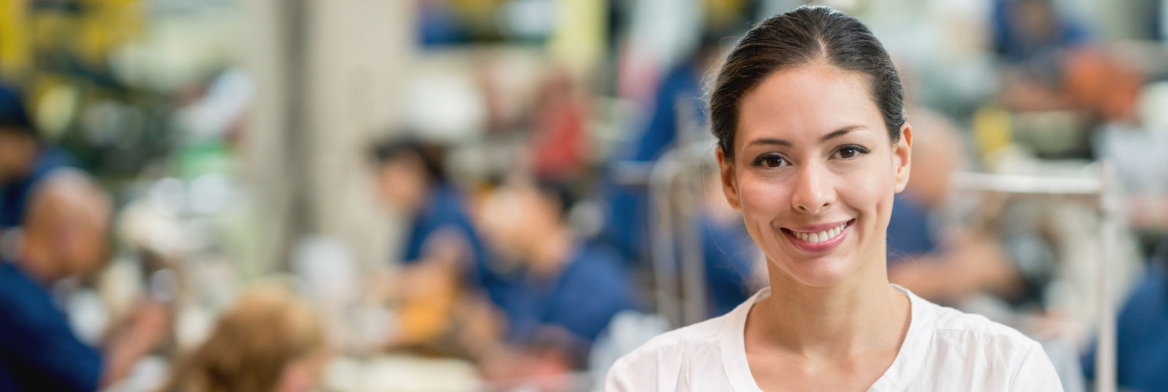 Smiling woman in a white shirt standing in a blurred office or café setting
