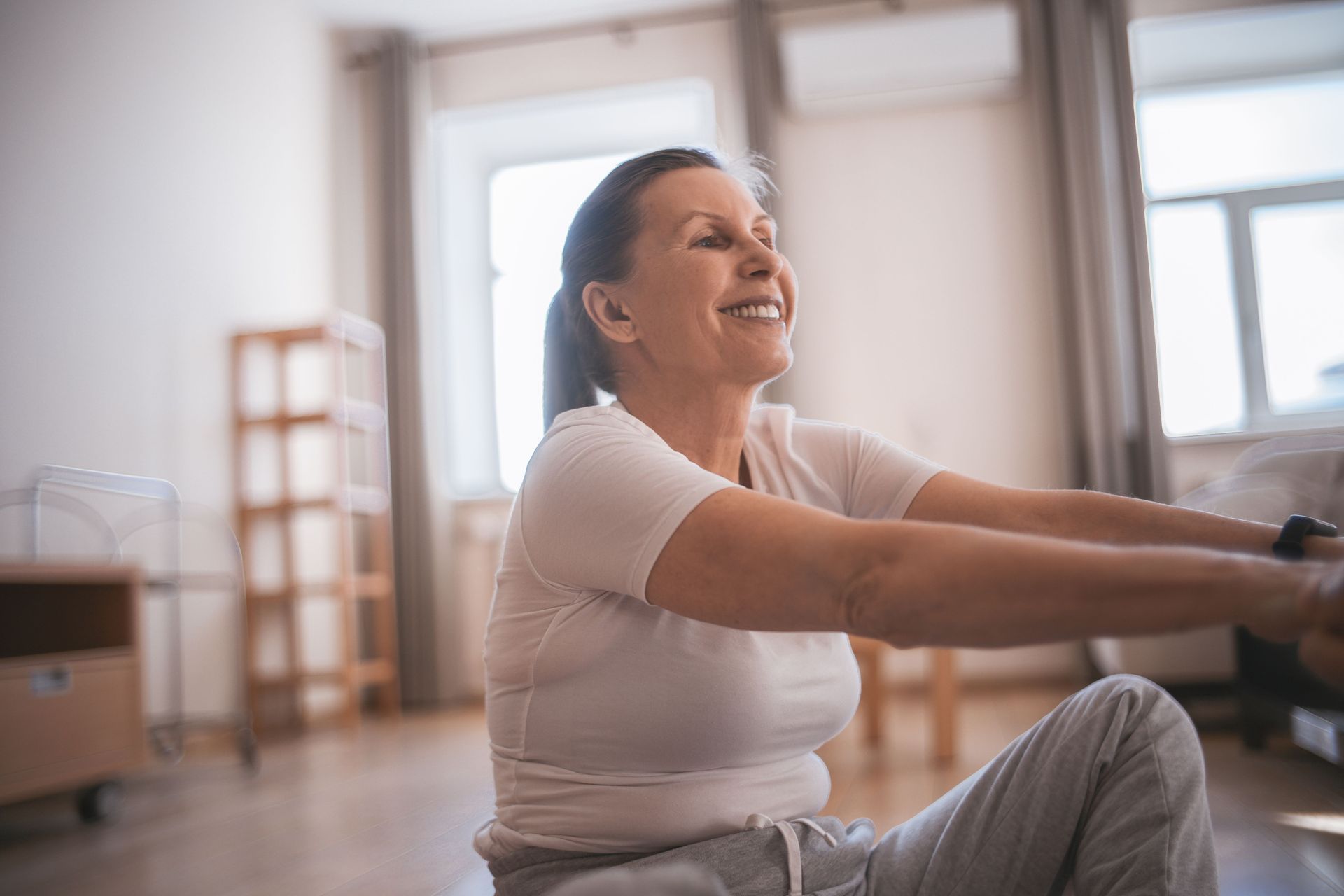 Physical therapist assisting a client with arm stretch in a clinic room