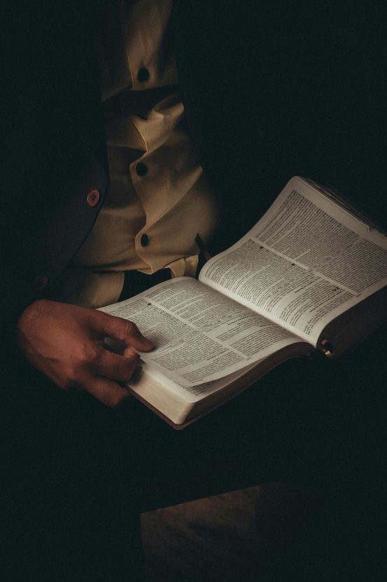 Hands holding an open book in dim light