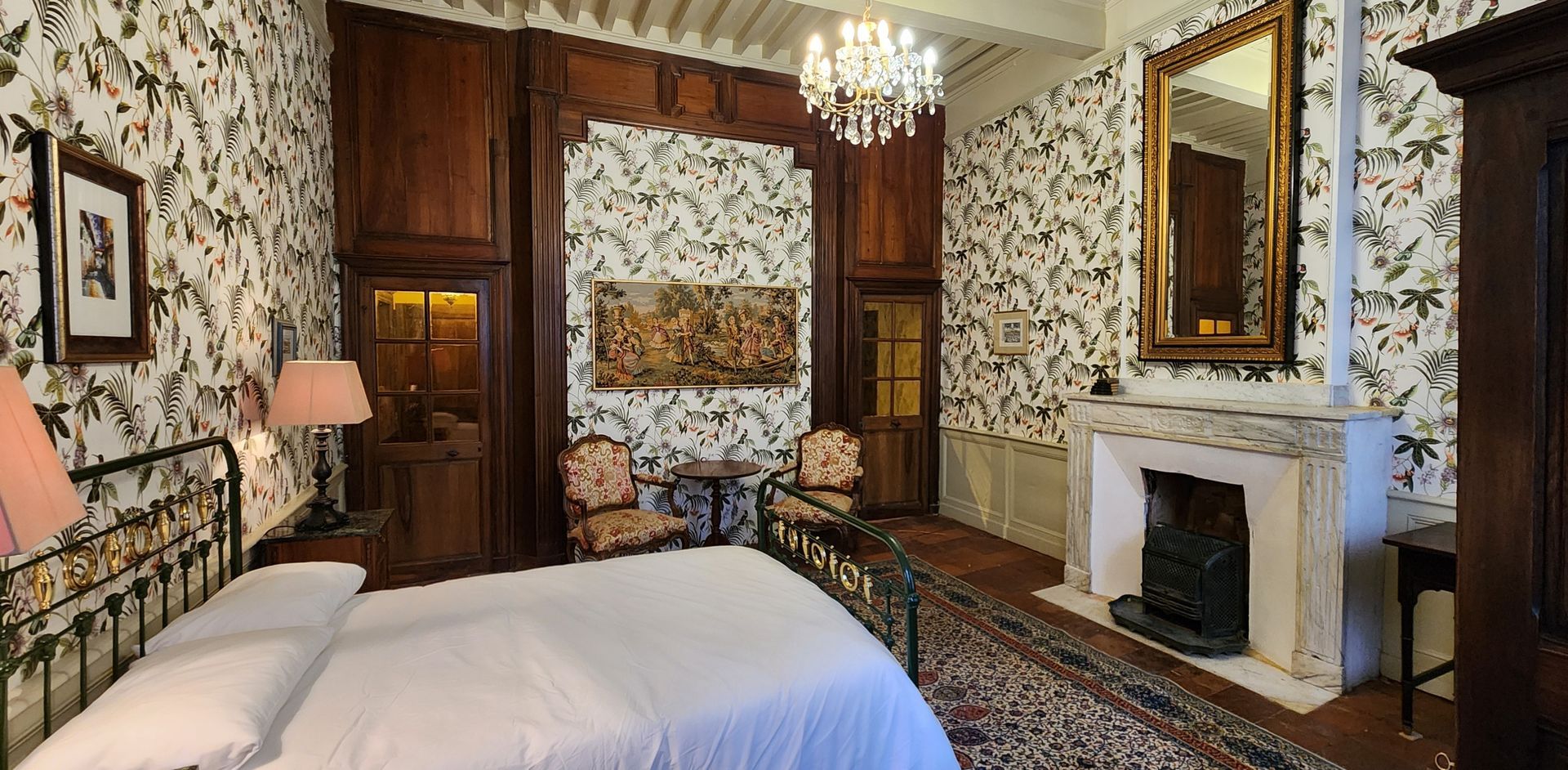une chambre avec un lit , une cheminée , des chaises et un miroir .