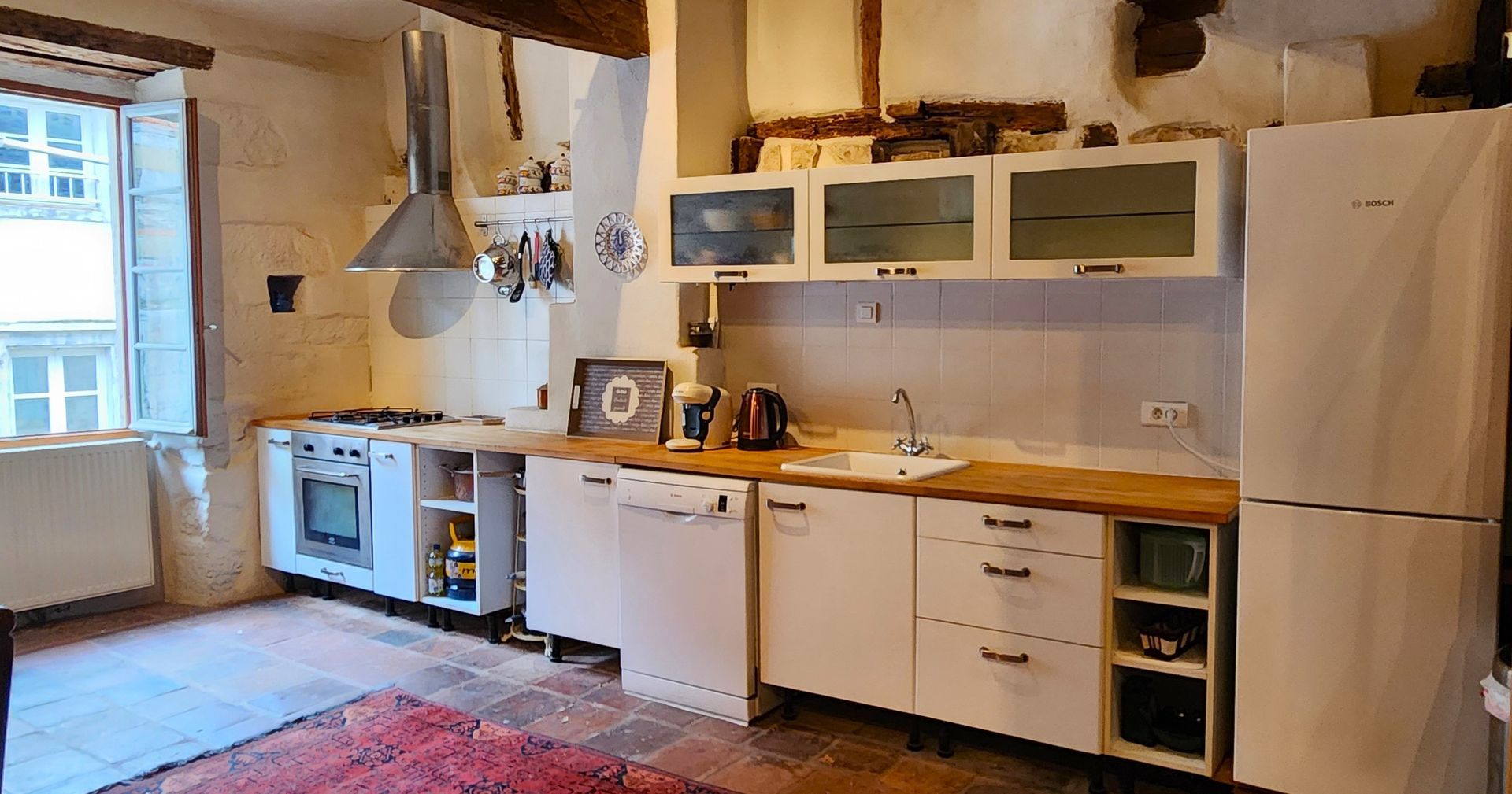 A kitchen with white cabinets , a refrigerator , a dishwasher , and a stove.
