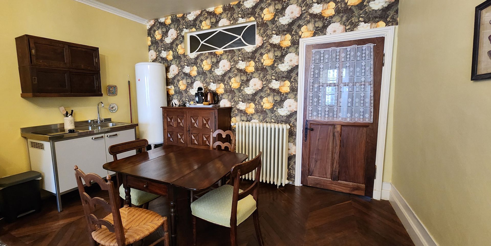 A dining room with a table and chairs and a refrigerator.