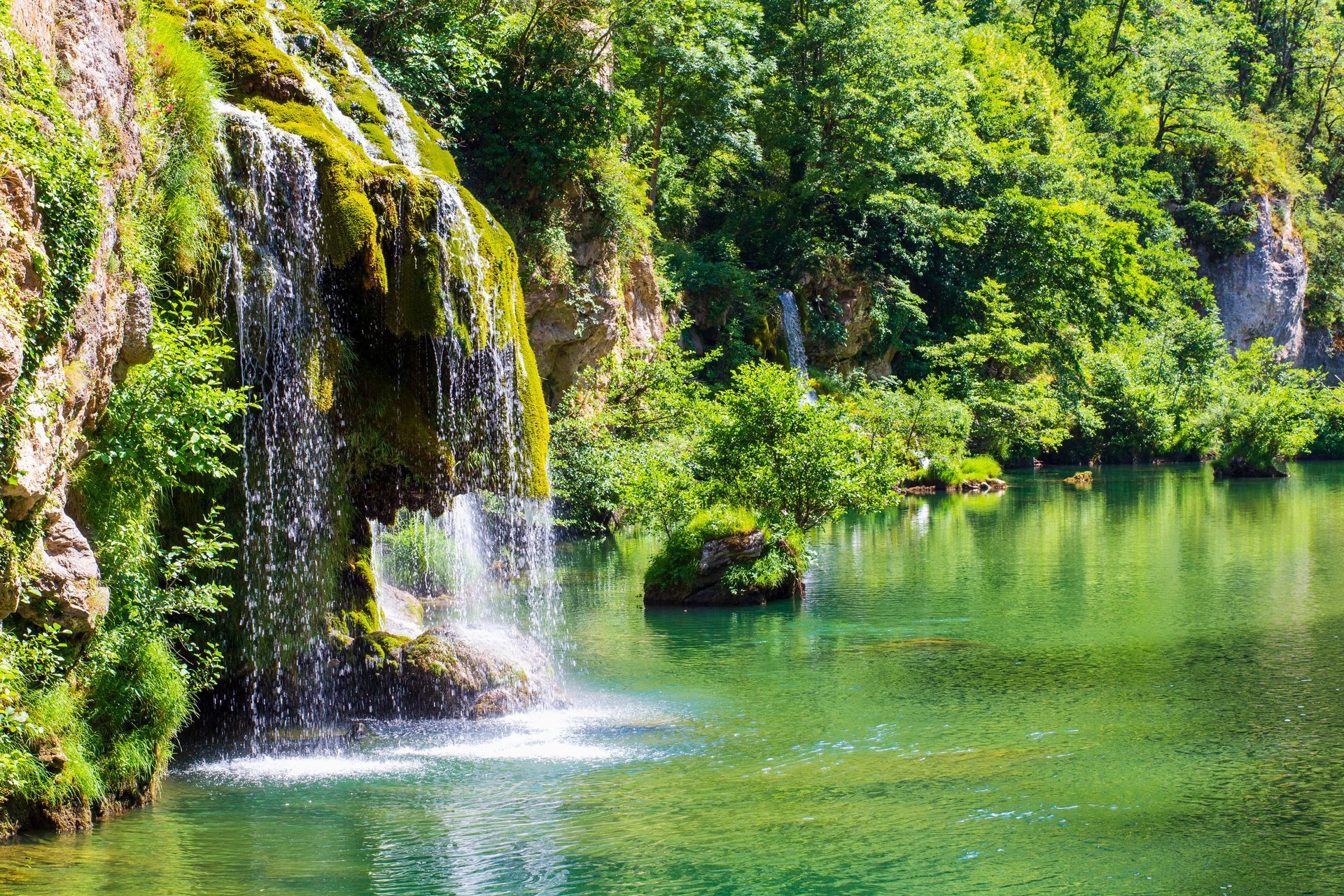 there is a waterfall in the middle of a lake surrounded by trees .