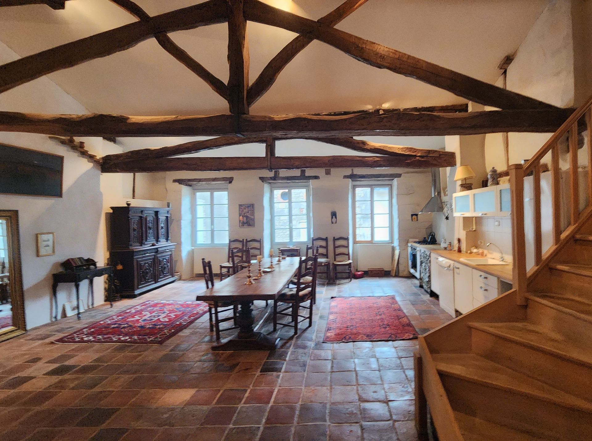 une grande pièce avec une table et des chaises et des escaliers