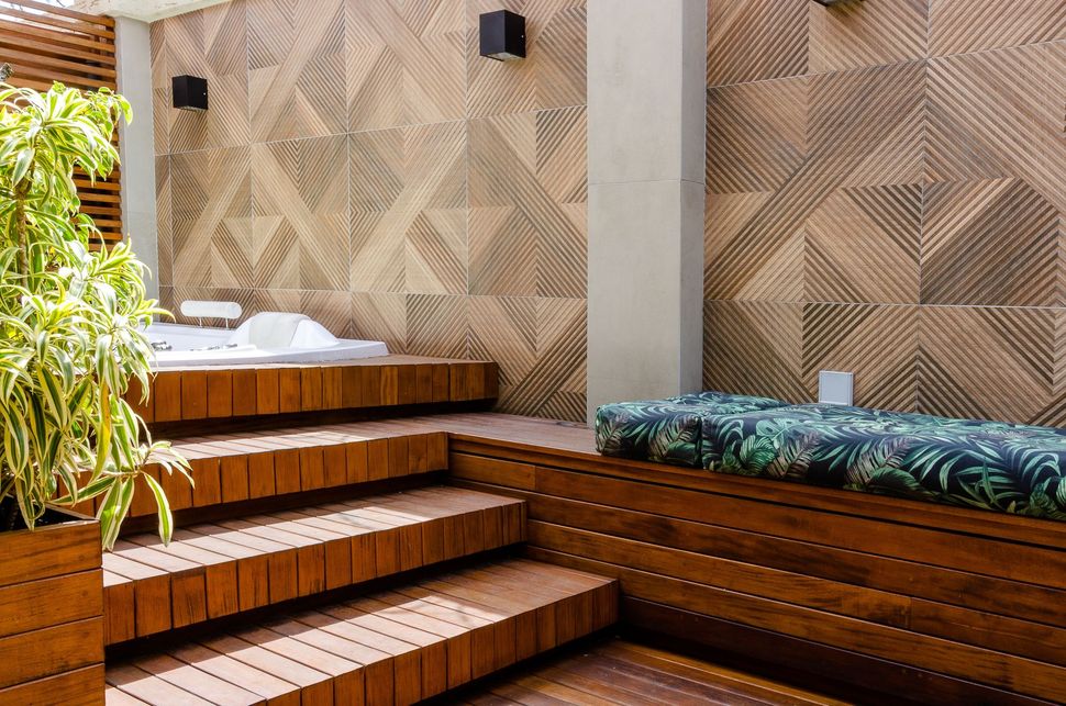 Wooden steps and bench seating in a modern patio with a woven wood wall and greenery