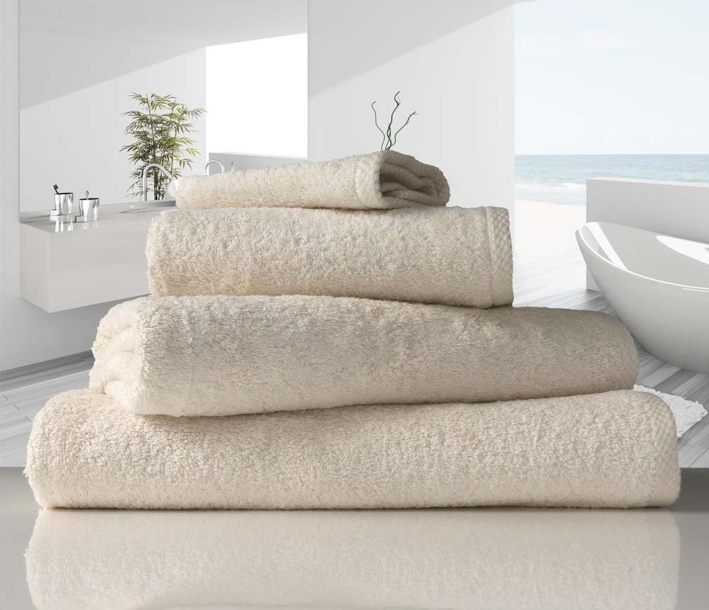 Natural unbleached organic cotton towels neatly piled near a bathtub